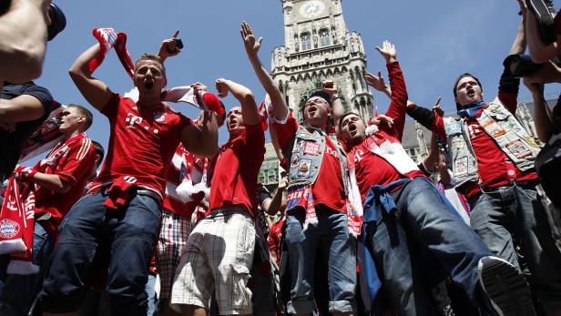 Eine Gruppe jubelnder Fußballfans des FC Bayern München vor dem Neuen Rathaus in München.