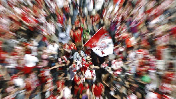 Eine Menschenmenge jubelt mit einer Bayern München Flagge.