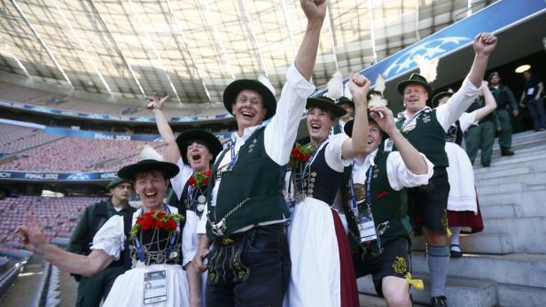 Eine Gruppe Menschen in Tracht jubelt auf der Tribüne eines Stadions.