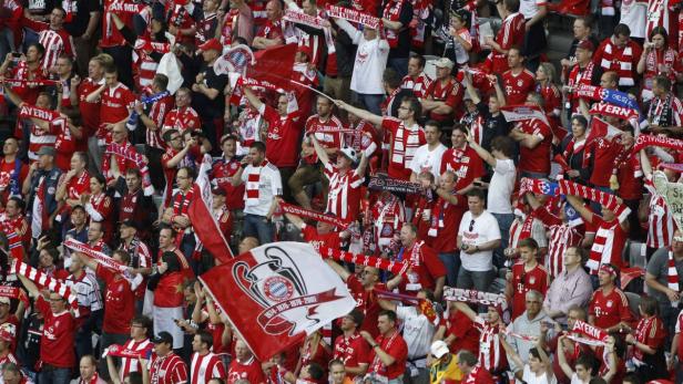 Eine große Menschenmenge, bekleidet mit rot-weißen Bayern München Trikots, feuert ihre Mannschaft an.