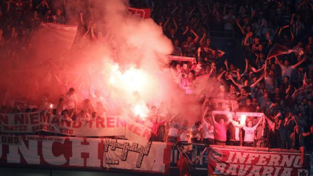 Fußballfans zünden Bengalos und schwenken Fahnen im Stadion.