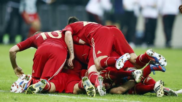 Mehrere Fußballspieler in roten Trikots liegen übereinander auf dem Rasen.