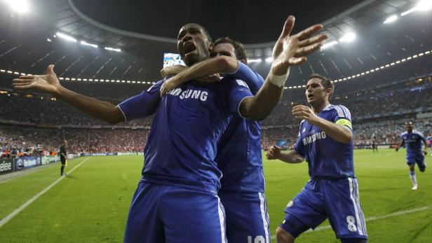 Didier Drogba feiert mit seinen Teamkollegen einen Sieg im Fußballstadion.
