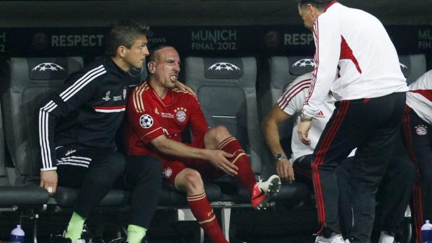 Fußballspieler Franck Ribéry sitzt verletzt auf der Bank, umgeben von Betreuern.