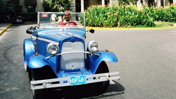 Ein blauer Oldtimer mit einem Fahrer in Kuba.