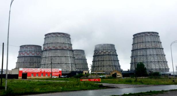 Mehrere Kühltürme eines Kraftwerks ragen in den bewölkten Himmel.