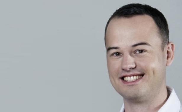 Dennius Bemmann, Mitbegründer studiVZ (c: netzdialog vorarlberg) Ein lächelnder Mann mit kurzen, dunklen Haaren vor einem grauen Hintergrund.