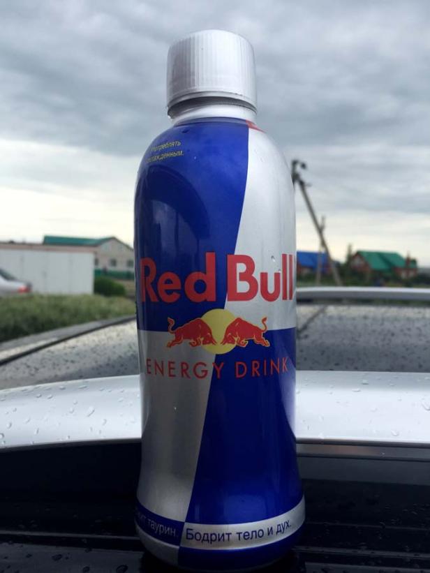 Eine Dose Red Bull Energy Drink steht auf einem Autodach.