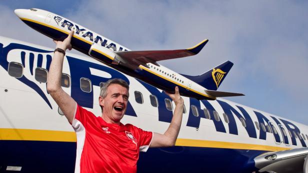 Ein Mann im roten Trikot hält ein Ryanair-Flugzeugmodell in die Höhe.