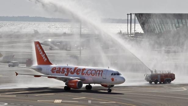 Ein EasyJet-Flugzeug wird auf dem Rollfeld mit Wasserfontänen von einem Feuerwehrfahrzeug begrüßt.