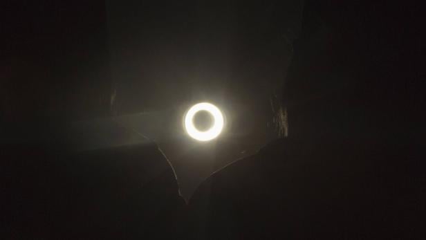 Eine Person hält ein Ringlicht im Dunkeln.