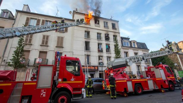 Feuerwehrleute bekämpfen einen Brand in einem Wohnhaus mit Drehleitern.