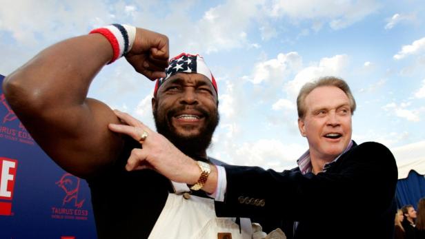 Mr. T und ein weiterer Mann posieren auf dem roten Teppich und zeigen ihre Muskeln.