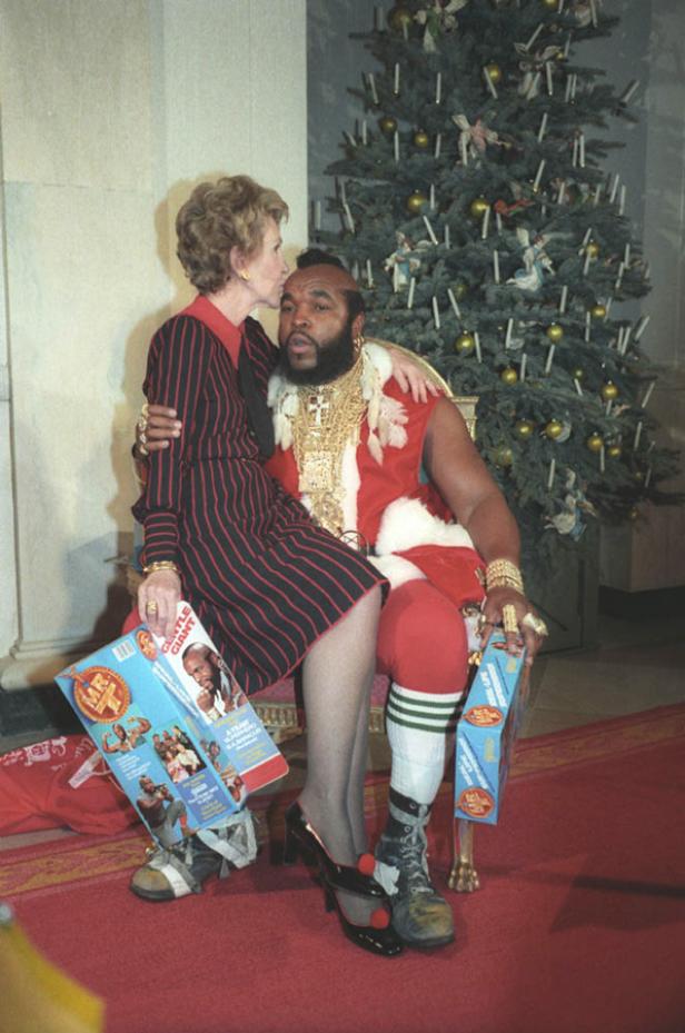 Nancy Reagan küsst Mr. T, der als Weihnachtsmann verkleidet ist, auf die Wange.