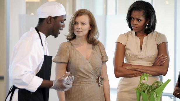 Ein Koch erklärt Michelle Obama und einer weiteren Frau etwas über eine Pflanze.