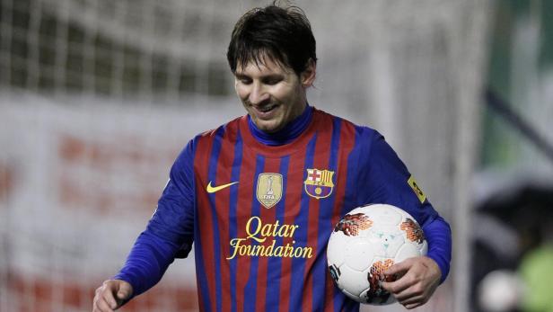 Lionel Messi im Trikot des FC Barcelona mit einem Fußball in der Hand.