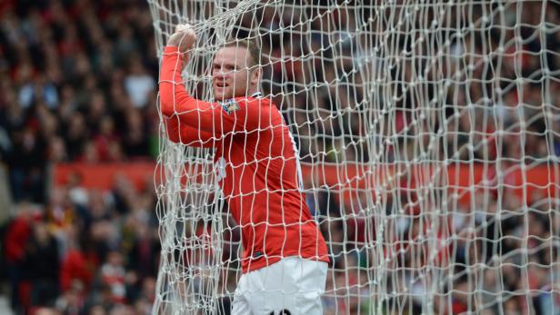 Wayne Rooney hängt im Netz eines Fußballtors.