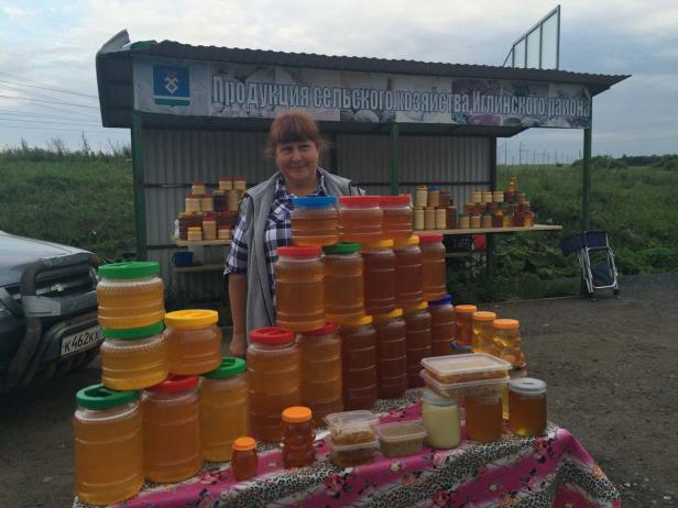 Eine Frau verkauft Honig auf einem Marktstand im Freien.