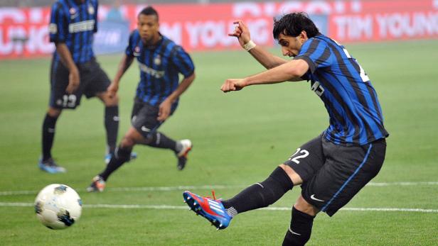 Ein Fußballspieler schießt den Ball auf einem grünen Rasen.