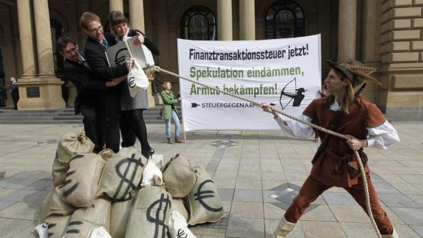 Als Robin Hood verkleideter Mann zieht an einem Seil, während Geschäftsleute an Säcken mit Dollar- und Eurozeichen ziehen.