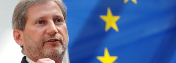 Ein Mann spricht vor einer EU-Flagge.