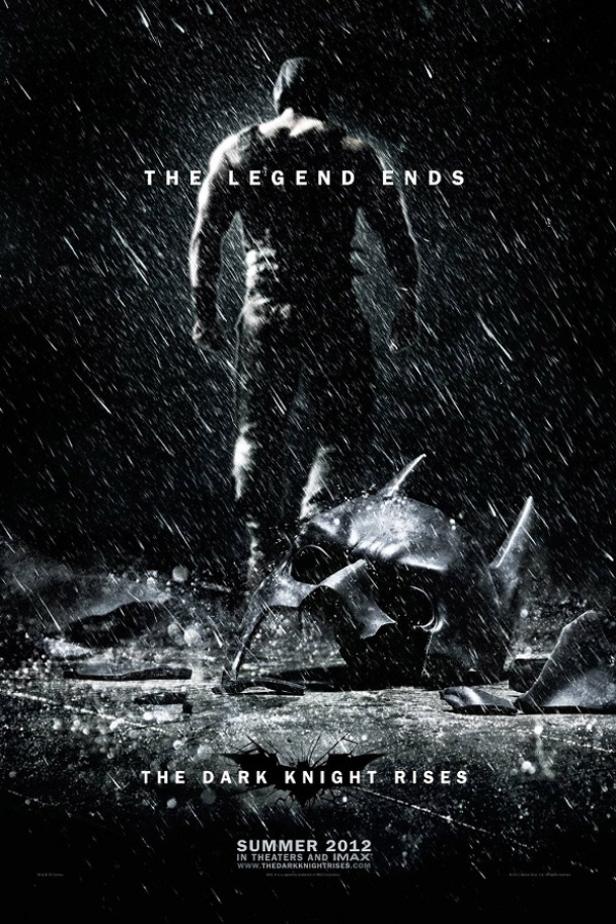 Ein Mann steht im Regen vor der zerstörten Batman-Maske, Plakat für „The Dark Knight Rises“.