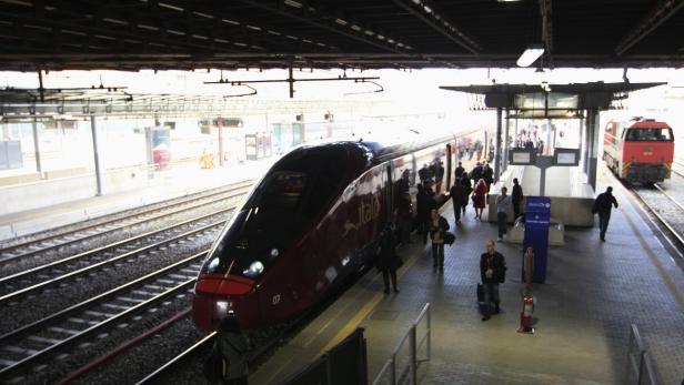Ein Italo-Hochgeschwindigkeitszug hält an einem Bahnsteig, während Fahrgäste ein- und aussteigen.