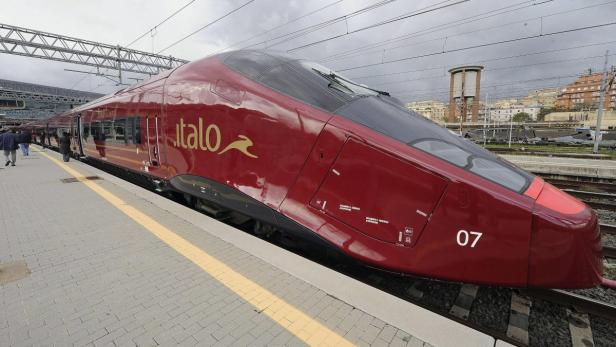Ein roter Hochgeschwindigkeitszug der Marke Italo steht am Bahnsteig.