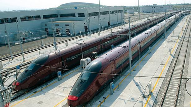 Zwei rote Hochgeschwindigkeitszüge stehen auf einem Bahnhofsgleis.
