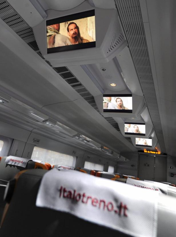 Im Innenraum eines Italo-Zuges laufen Filme auf Bildschirmen über den Sitzen.