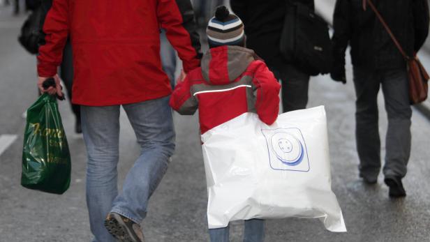 Ein Vater und sein Kind tragen Einkaufstüten auf einer belebten Straße.
