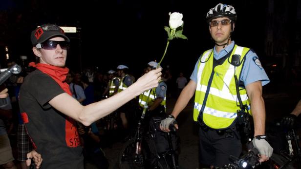 Ein Demonstrant überreicht einem Polizisten eine weiße Rose.