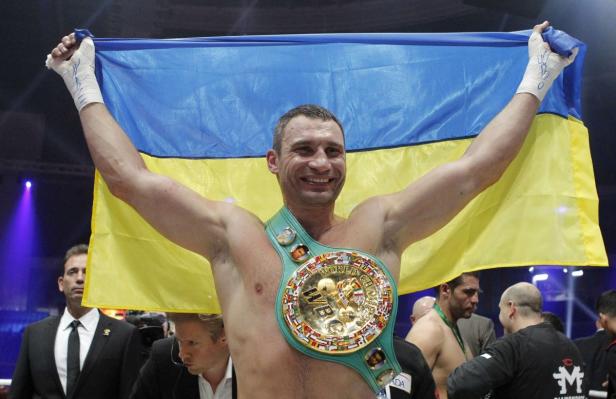 Vitali Klitschko mit dem ukrainischen Flagge und einem Weltmeistergürtel.