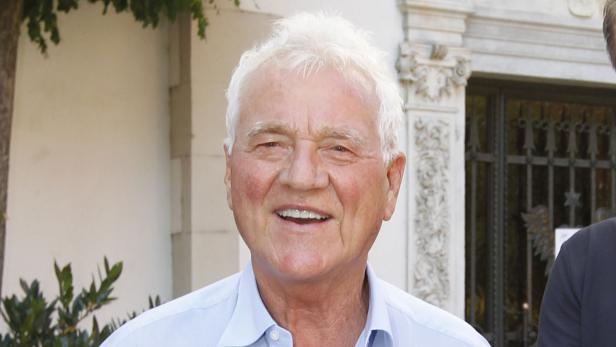 Ein älterer Mann mit weißem Haar lächelt in die Kamera.