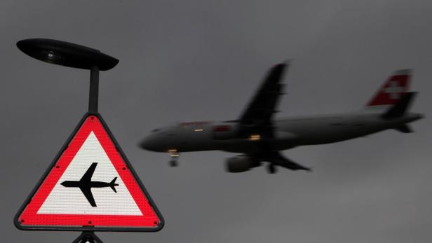 Ein Warnschild vor einem landenden Flugzeug der Swiss International Air Lines.