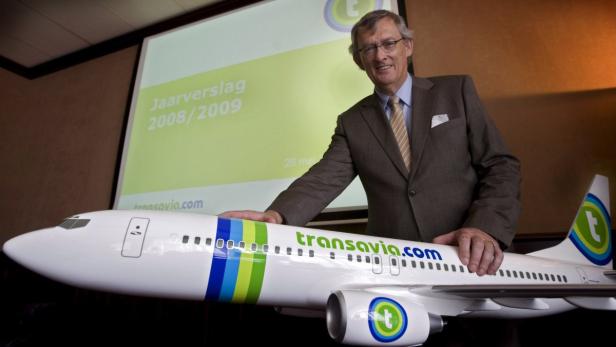 Ein Mann im Anzug präsentiert ein Modellflugzeug von Transavia vor einer Leinwand mit der Aufschrift „Jaarverslag 2008/2009“.