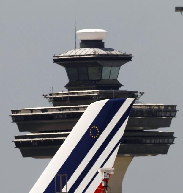 Das Leitwerk eines Flugzeugs mit den EU-Sternen vor einem Kontrollturm.