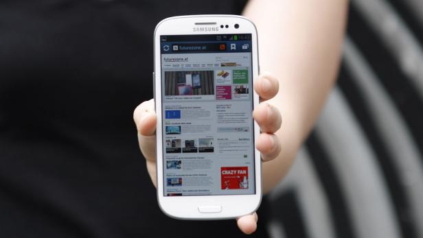 Eine Hand hält ein Samsung Smartphone mit der Webseite futurezone.at.