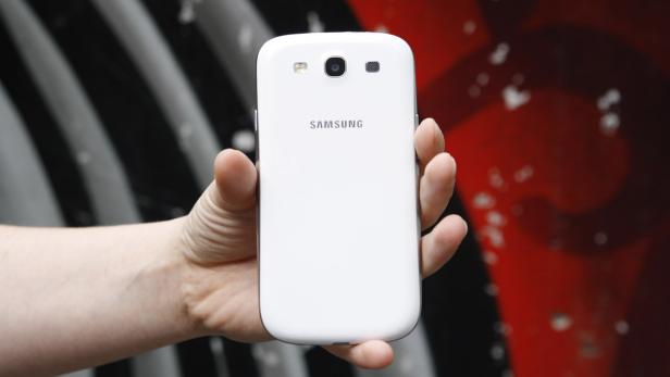 Eine Hand hält ein weißes Samsung Smartphone.