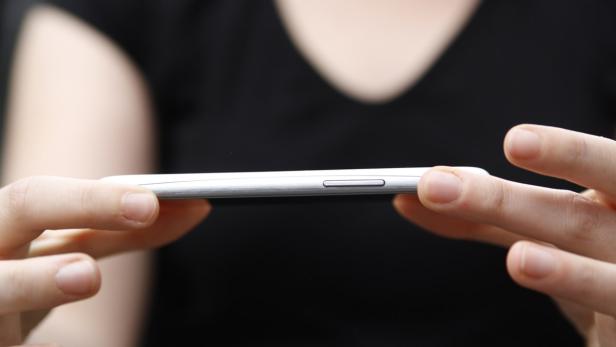 Eine Person hält ein silbernes Smartphone in ihren Händen.