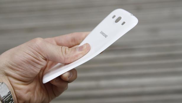 Eine Hand hält die weiße Rückseite eines Samsung Smartphones.