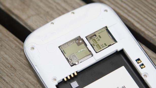 Die Rückseite eines geöffneten Mobiltelefons zeigt den Akku, die SIM-Karte und den SD-Kartensteckplatz.