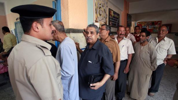 Eine Schlange von Männern steht in einem Raum, möglicherweise um zu wählen.