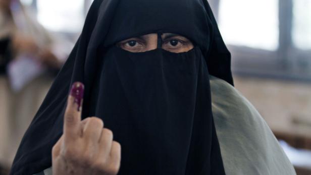 Eine Frau mit Niqab zeigt ihren mit Tinte markierten Finger nach der Stimmabgabe.