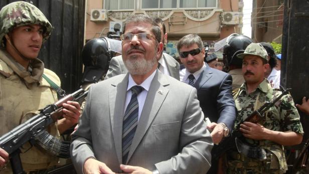 Mohammed Mursi wird von Sicherheitskräften mit Gewehren eskortiert.