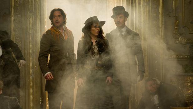 Robert Downey Jr., Noomi Rapace und Jude Law in einer Szene voller Rauch.