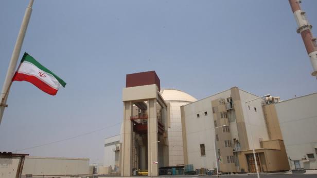 Eine Ansicht des iranischen Atomkraftwerks Buschehr mit der iranischen Flagge im Vordergrund.