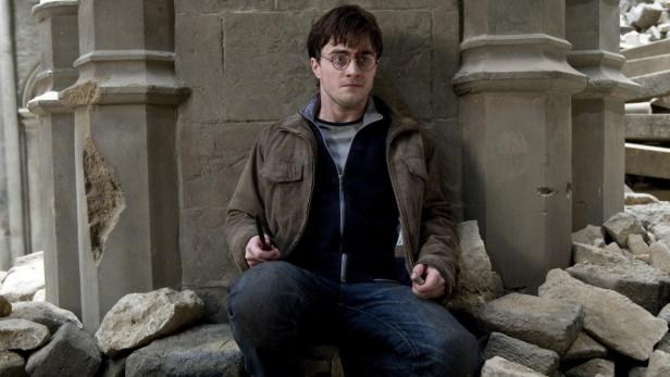 Daniel Radcliffe als Harry Potter inmitten von Trümmern mit einem Zauberstab in der Hand.