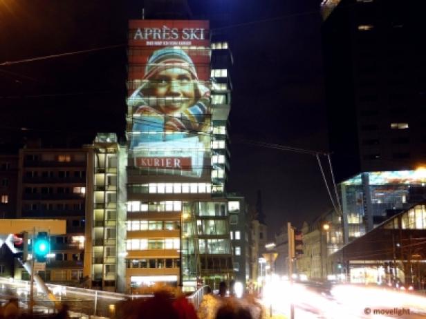 Ein Hochhaus in der Nacht mit einer Projektion von „Après Ski“ und dem Kurier-Logo.