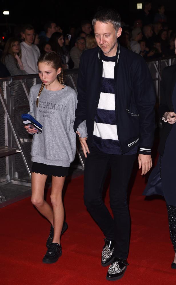 Ein Mann und ein junges Mädchen gehen über einen roten Teppich.